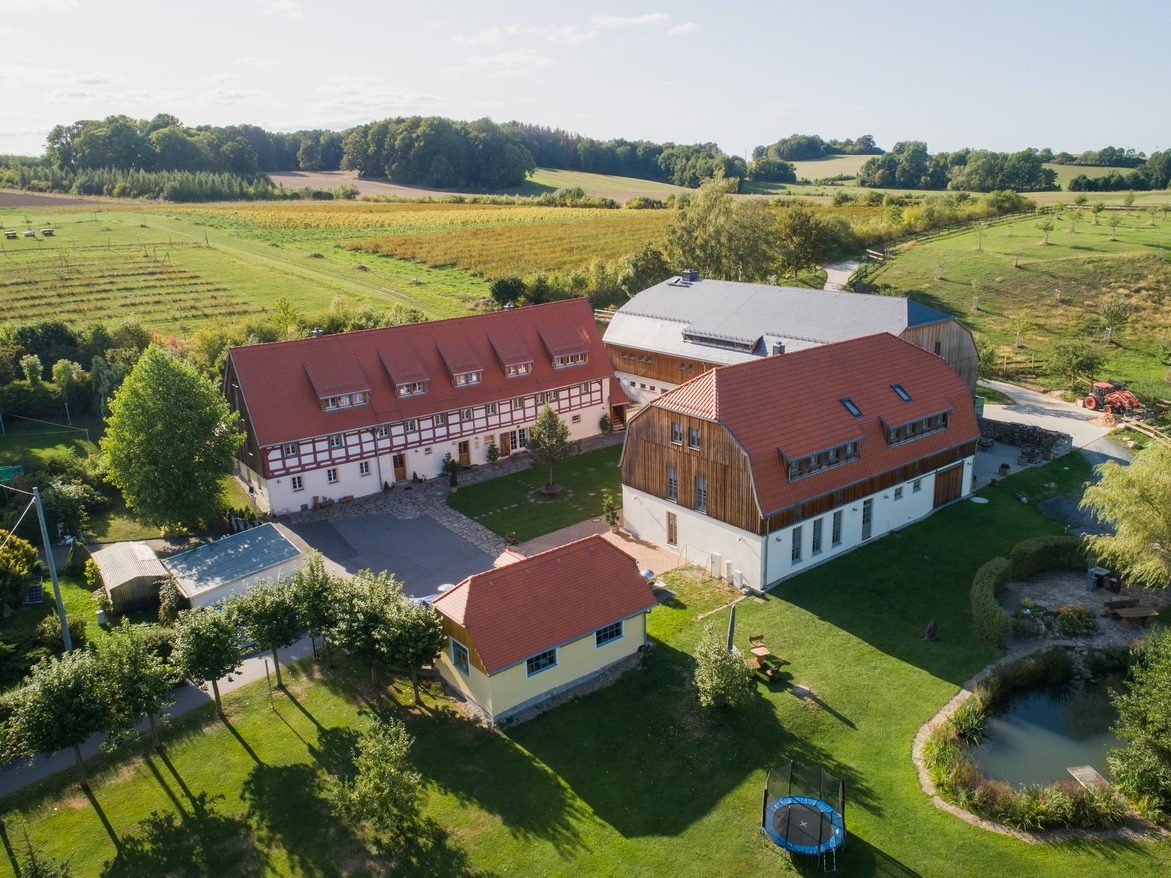Luftaufnahme des Dreiseithofs Sohra mit Fachwerkhaus, Gästehaus und Teich zwischen Feldern