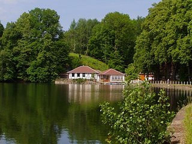 Das Bootshaus der Höllmühle am stillen Mühlteich, umgeben von Wald