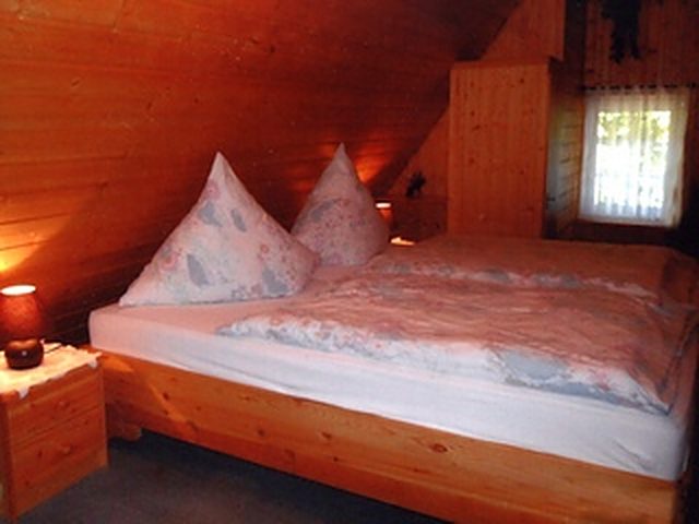 Gästezimmer der Pension Höllmühle mit Doppelbett unter holzvertäfelter Dachschräge