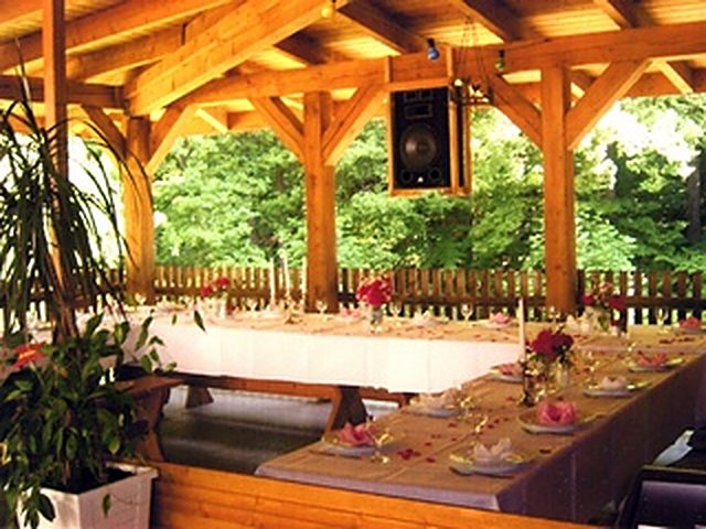 Die überdachte Holzterrasse der Höllmühle mit festlich eingedeckter Tafel und Blick ins Grüne
